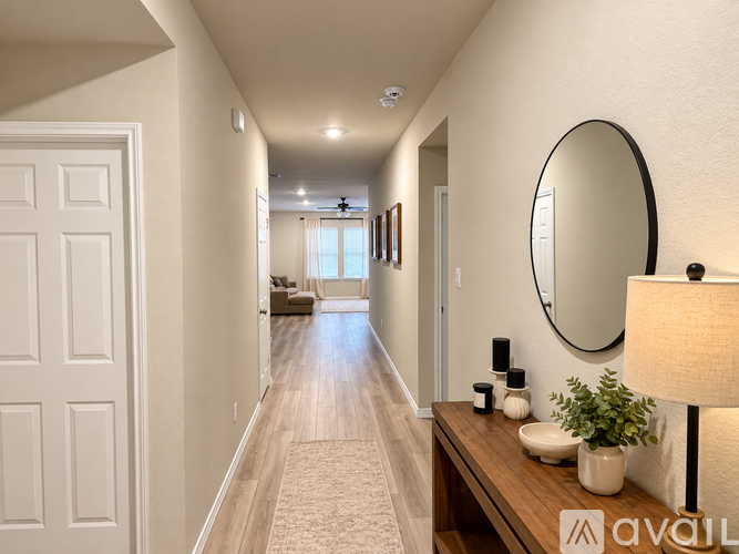 A hallway with a mirror, lamp, and a plant on a table.