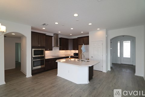 A modern kitchen with a center island and wooden floors.