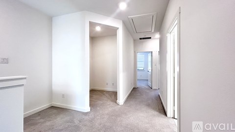 A spacious room with white walls and carpeted floor.