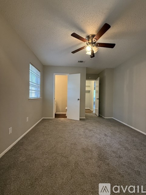 A spacious room with a ceiling fan and carpeted floor.