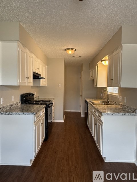 A kitchen with white cabinets and a granite countertop.