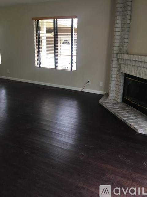 A living room with a fireplace and dark wood floors.