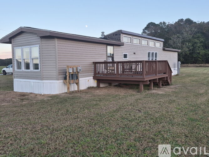 A house with a deck and a car parked in the driveway.