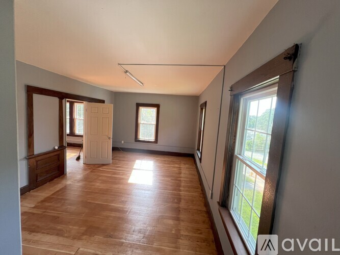 A room with wooden floors and a large window on the right side.