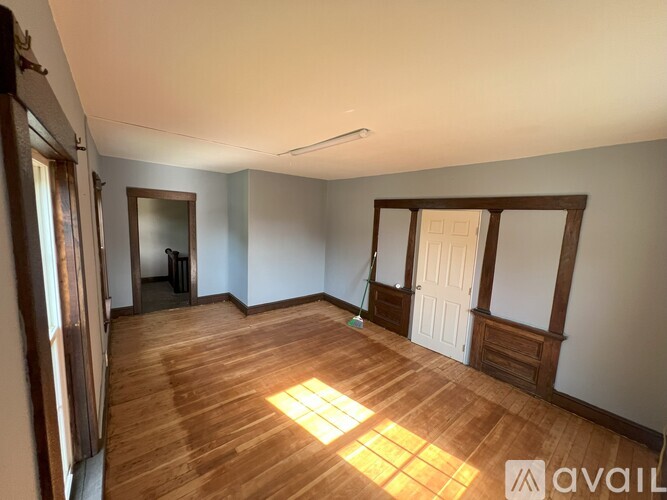 A room with wooden floors and a window letting in sunlight.