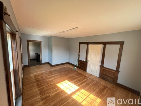 A room with wooden floors and a window letting in sunlight.