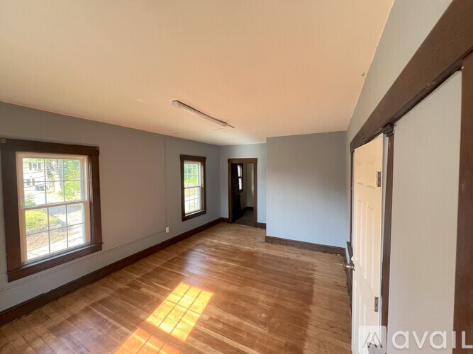 A room with wooden flooring and a window on the left side.