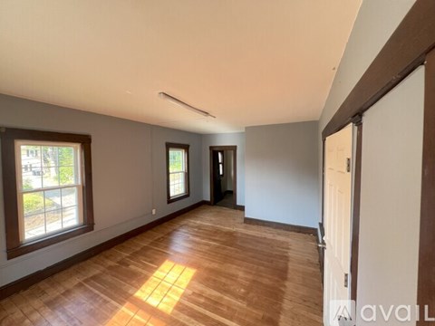 A room with wooden flooring and a window on the left side.