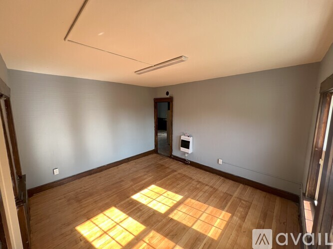 A room with wooden flooring and a white ceiling with a light fixture.