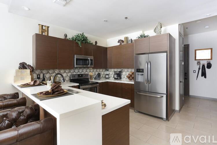 A modern kitchen with brown and white cabinets, a white island, and stainless steel appliances.