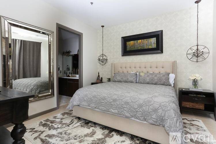 A bedroom with a large bed, a mirror, and a painting on the wall.