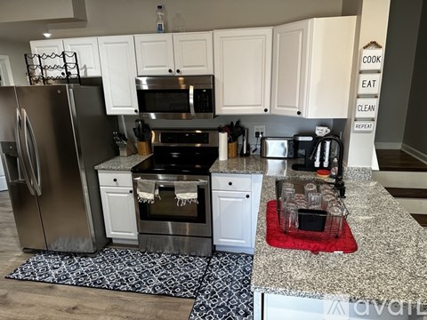 A kitchen with white cabinets and a black and white patterned rug.