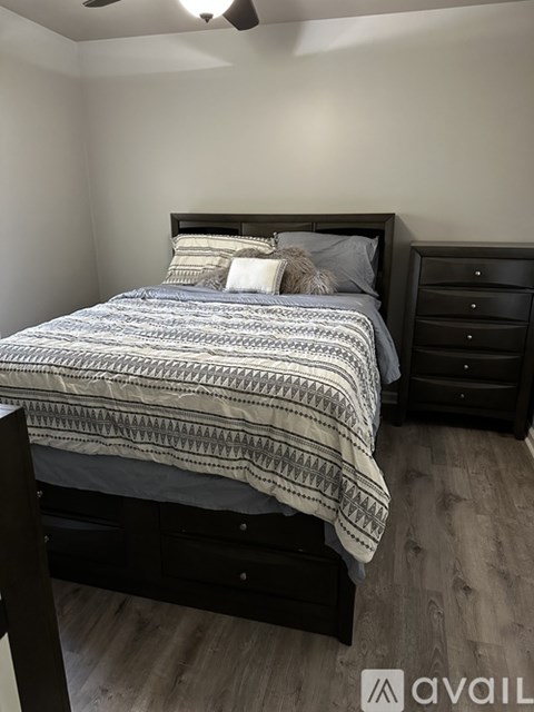 A bedroom with a bed, dresser, and ceiling fan.