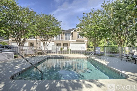 A pool surrounded by trees and a building in the background.