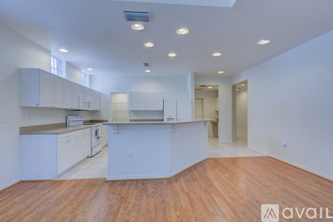 A spacious kitchen with white cabinets and wooden floors.