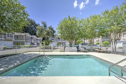 A swimming pool surrounded by trees and a fence.