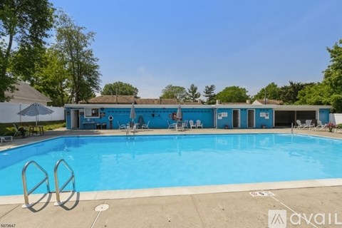 A large blue swimming pool with a diving board and a small building in the background.