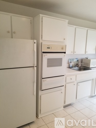 A white kitchen with a refrigerator, oven, and sink.