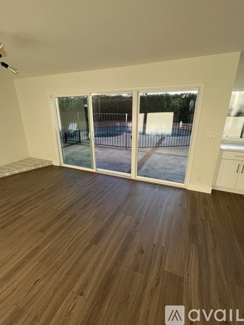 A room with wooden flooring and sliding glass doors leading to a patio.
