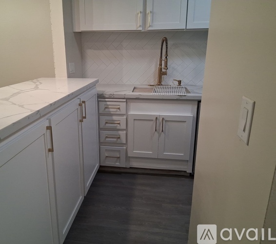 A kitchen with white cabinets and a marble countertop.