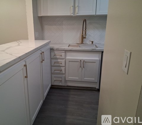 A kitchen with white cabinets and a marble countertop.