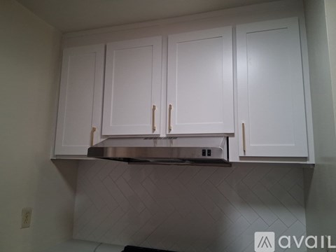 A kitchen with white cabinets and a stainless steel range hood.