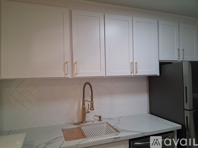A kitchen with white cabinets and a black refrigerator.