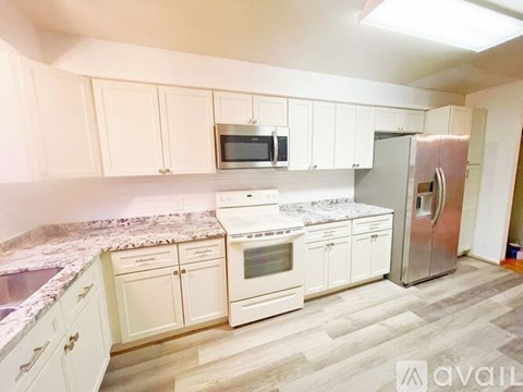 A kitchen with white cabinets and a marble countertop.