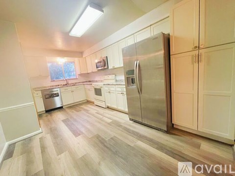 A kitchen with a refrigerator, oven, and cabinets.