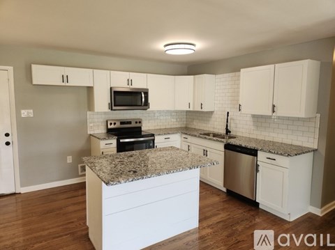 A kitchen with granite countertops and white cabinets.