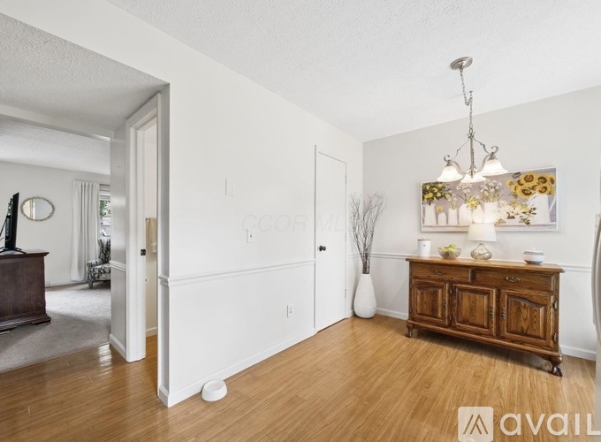 A room with a wooden floor and a brown cabinet with a chandelier hanging from the ceiling.