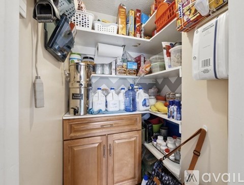 A kitchen pantry with a white fridge and a brown cupboard.