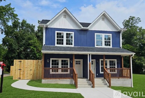 A blue and white house with a porch and a wooden fence.