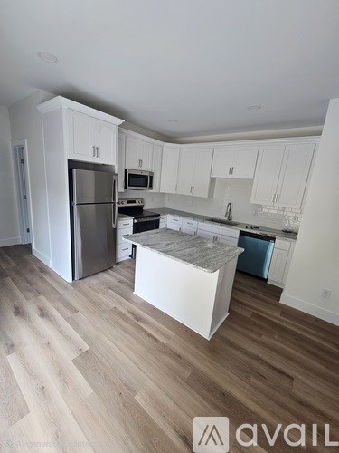 A kitchen with white cabinets and a wooden floor.
