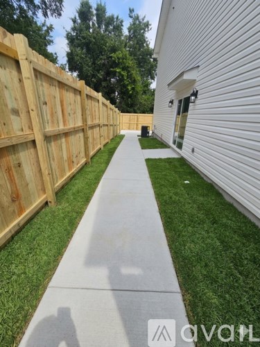 A wooden fence runs along the side of a white building.