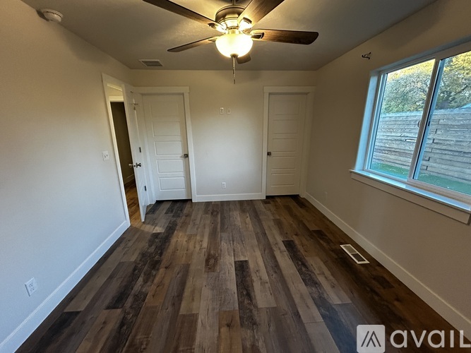A room with a ceiling fan and wooden flooring.