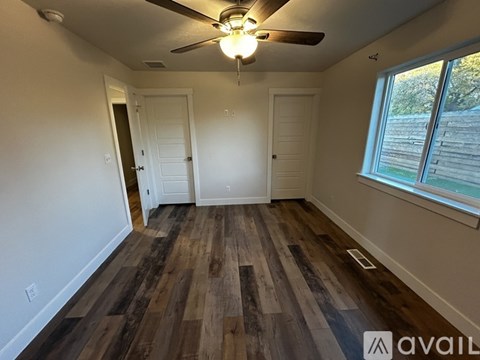 A room with a ceiling fan and wooden flooring.