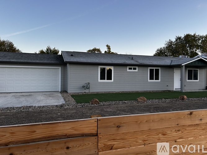 A house with a grey roof and a white garage door is available for sale.