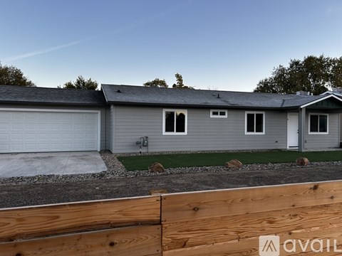 A house with a grey roof and a white garage door is available for sale.