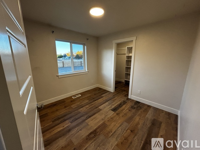 A room with wooden flooring and a window overlooking a parking lot.