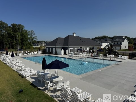 A large outdoor swimming pool surrounded by lounge chairs and umbrellas.