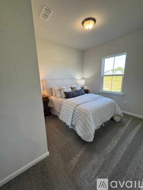 A bedroom with a bed, nightstand, and window.