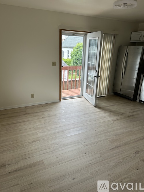 A room with wooden flooring and a sliding glass door leading to a balcony.