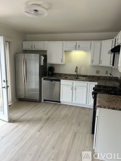 A kitchen with white cabinets and a refrigerator.