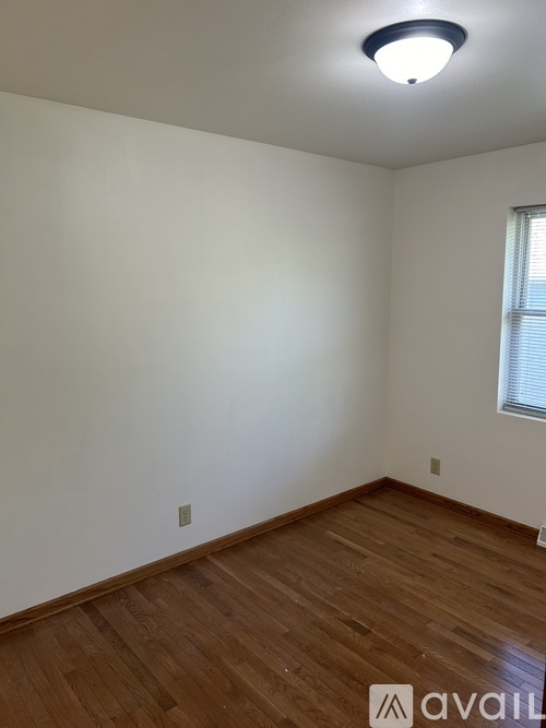 A room with wooden flooring and a window with blinds.