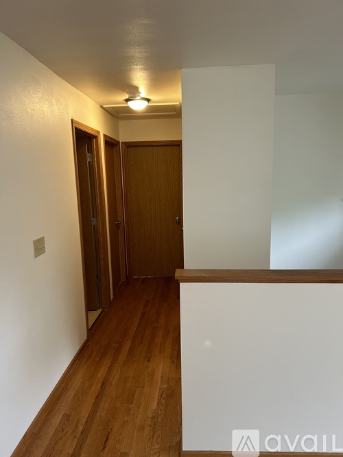 A hallway with wooden floors and white walls.