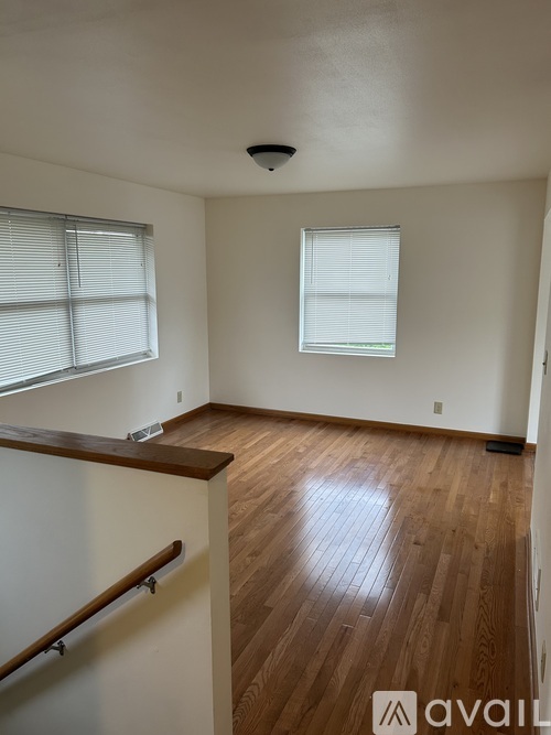 A room with wooden floors and two windows.
