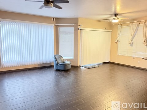 A spacious room with a ceiling fan and a chair.