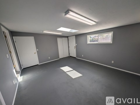 A spacious room with grey walls and a window showing trees outside.