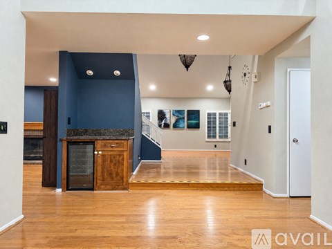 A spacious living room with a dark blue accent wall and a wooden floor.